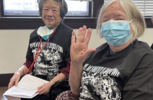 On the left, CID organizer Sue Kay sits at a Sound Transit board meeting in Union Station wearing a shirt that reads ''DISPLACEMENT IS DESTRUCTION.'' COURTESY OF PUGET SOUND SAGE